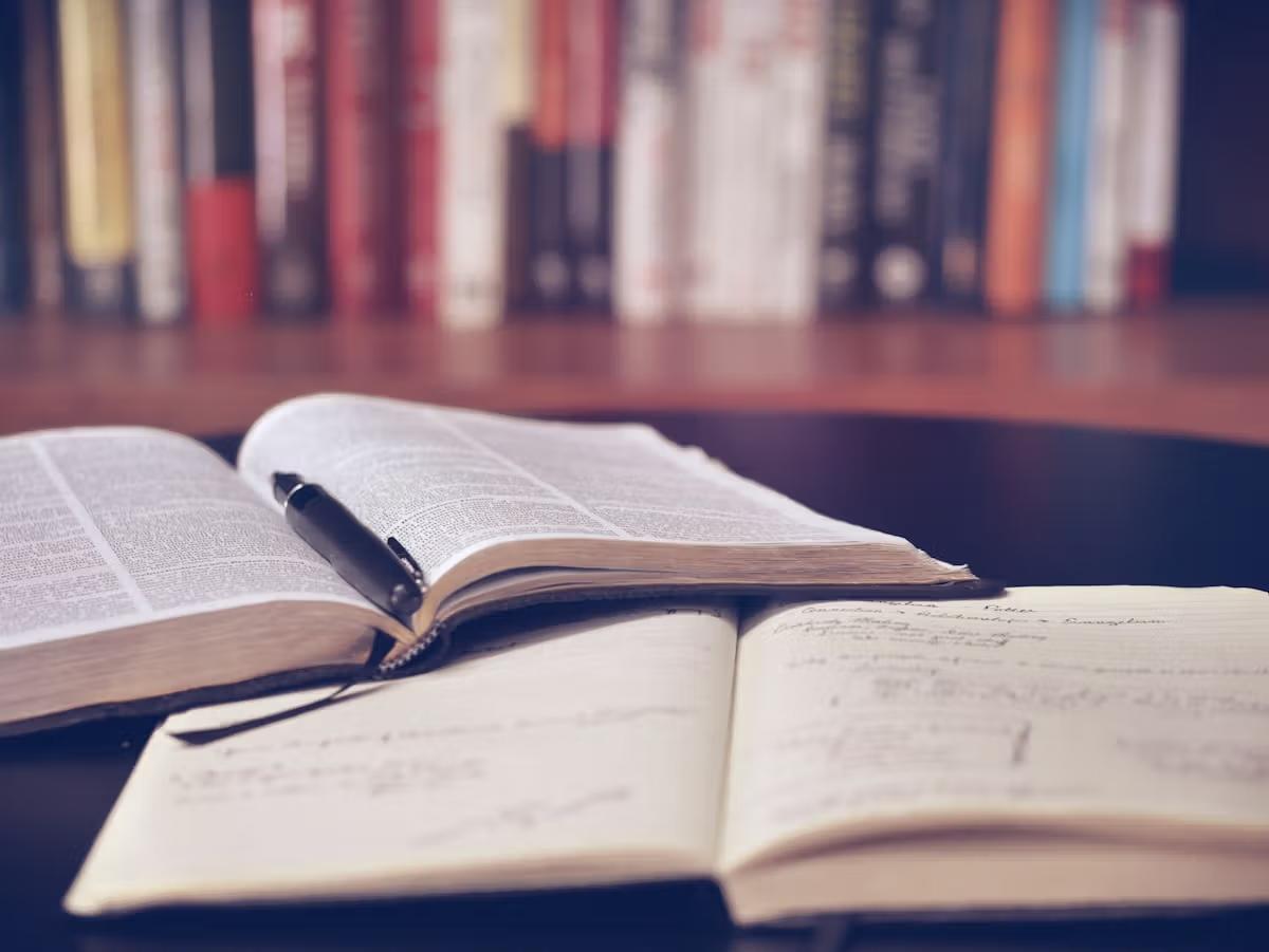 Open books and study materials on a desk with warm lighting